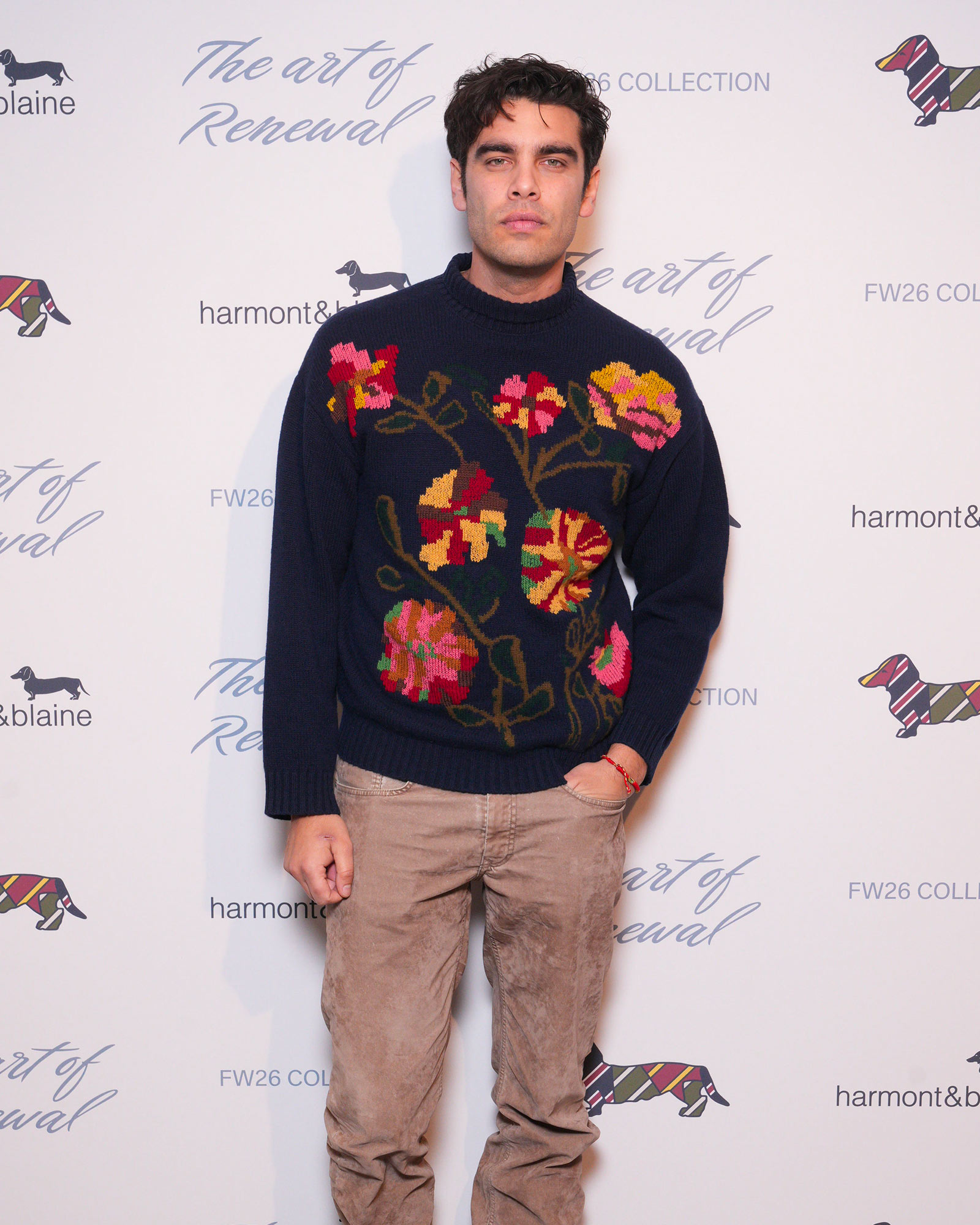 Uomo con maglione blu con fiori ricamati e pantaloni beige