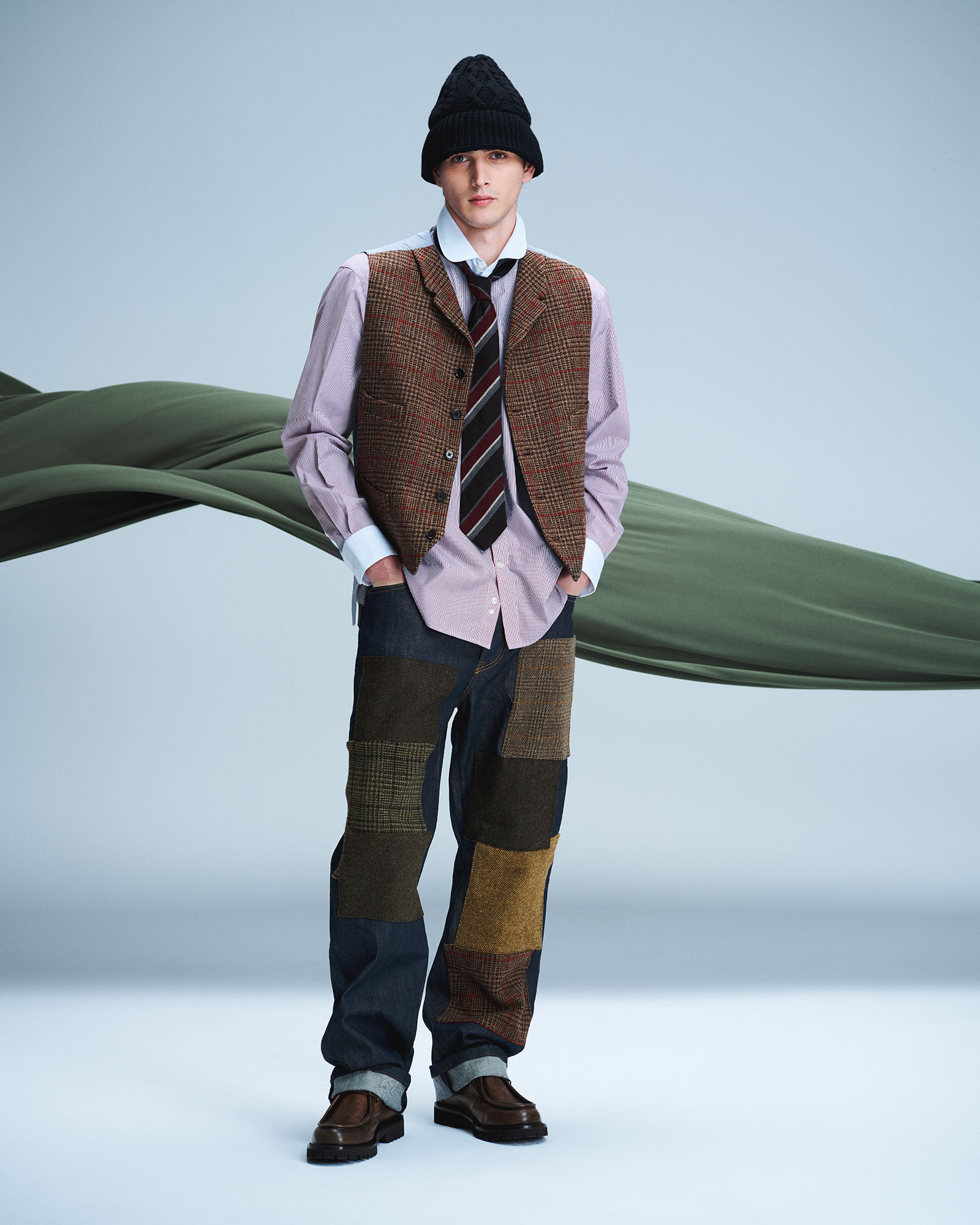 Uomo con camicia, gilet a quadri e pantaloni patchwork, con berretto nero e mocassini