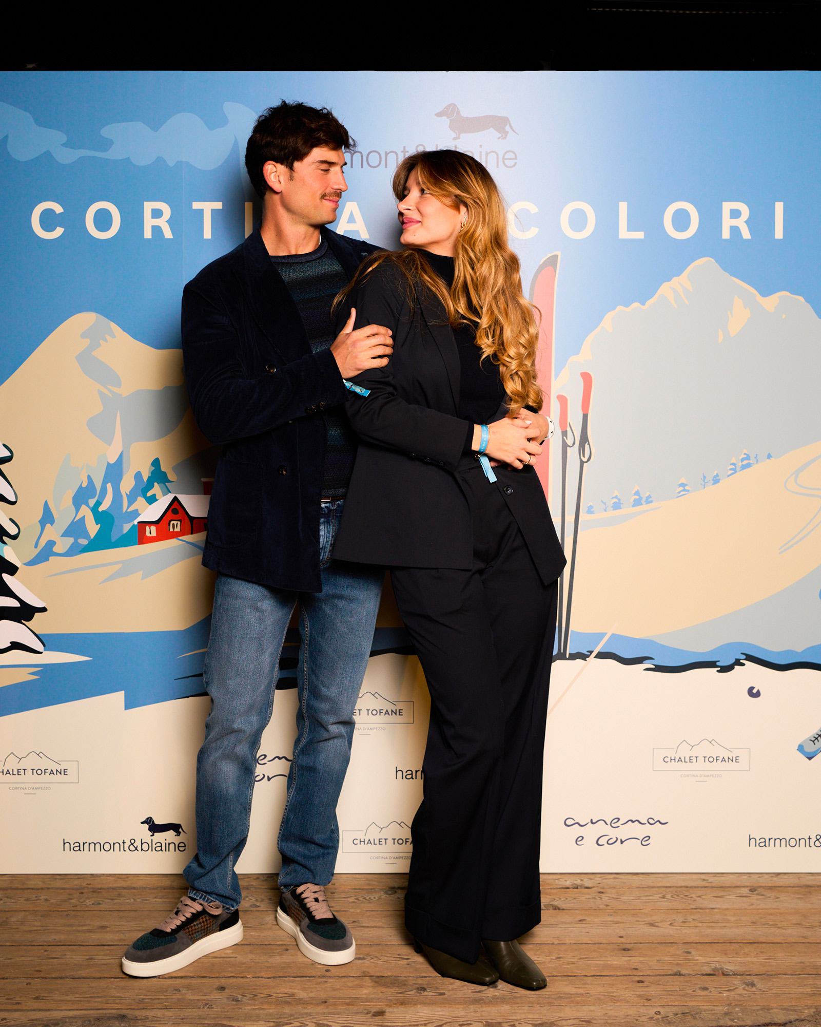 Coppia in look eleganti posando davanti al backdrop Cortina a Colori.