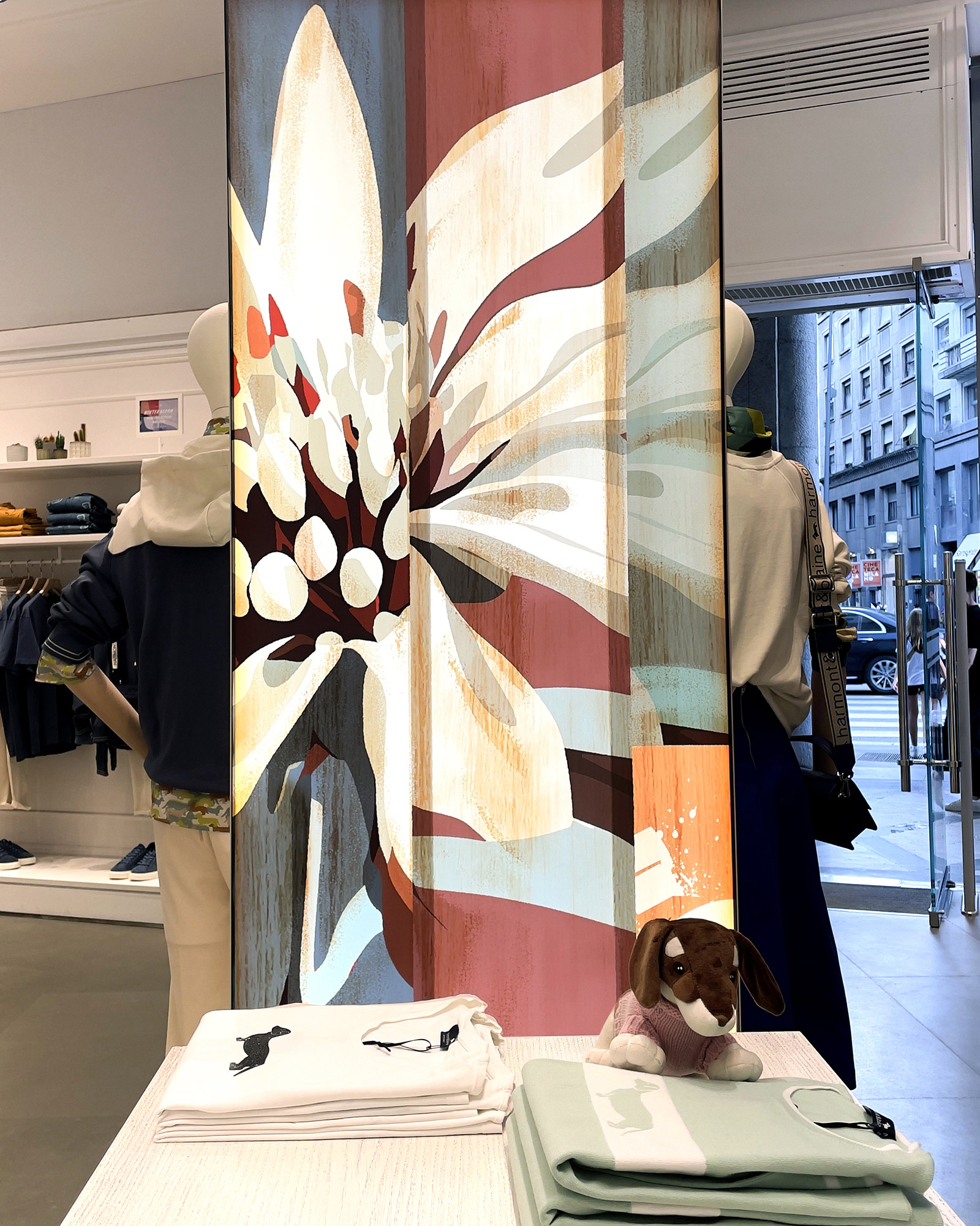 Vetrina Harmont & Blaine FW25 con grande fiore stilizzato e outfit denim e casual.