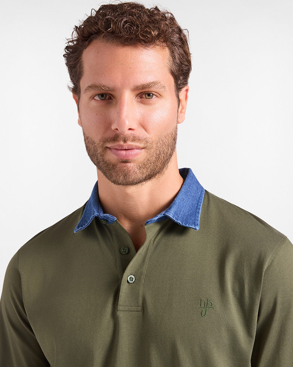 Per la categoria polo HB Jeans, un modello indossa una polo verde militare a maniche lunghe con colletto in denim blu a contrasto e un piccolo logo ricamato tono su tono sul petto, su sfondo chiaro.