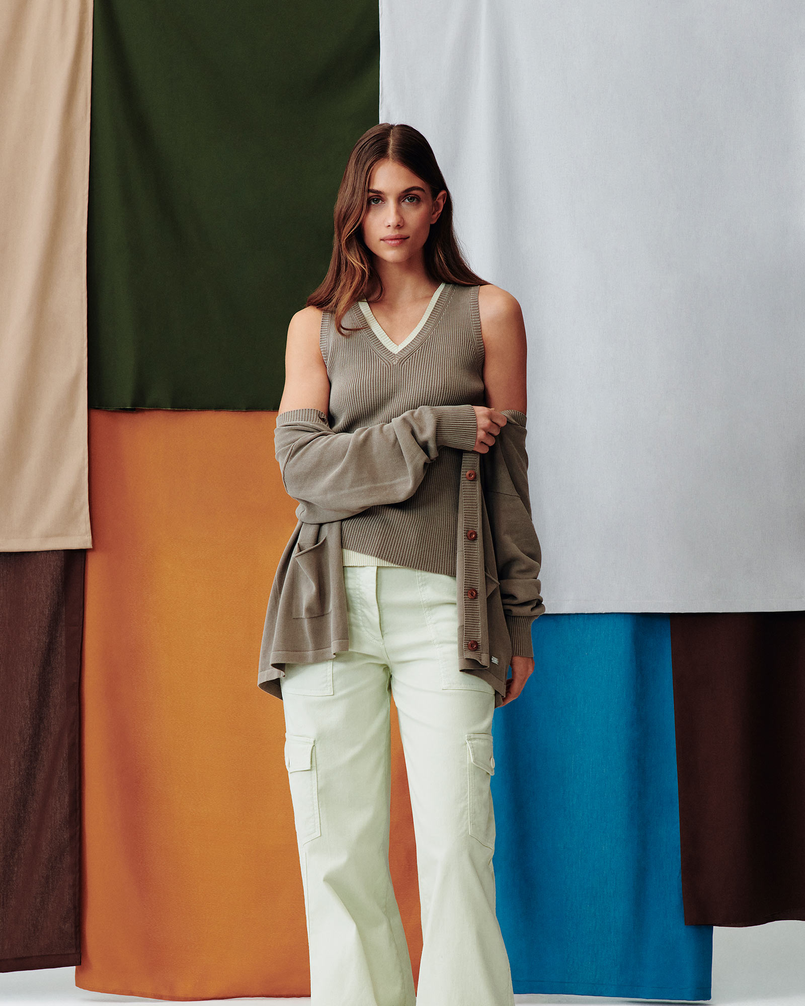 Modello uomo con camicia gialla e pantaloni color pesca su sfondo colorato.