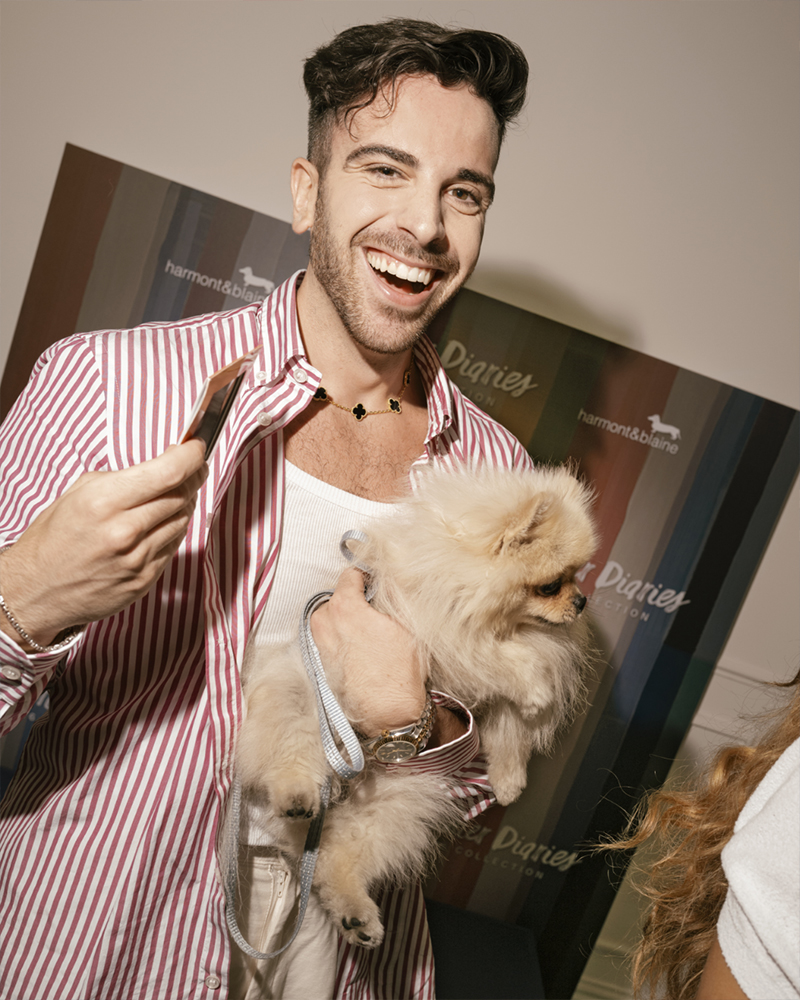 Uomo sorridente con cane all'evento Harmont & Blaine Summer Diaries.