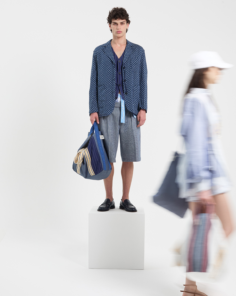 Modello con giacca blu e pantaloncini nella collezione estiva.