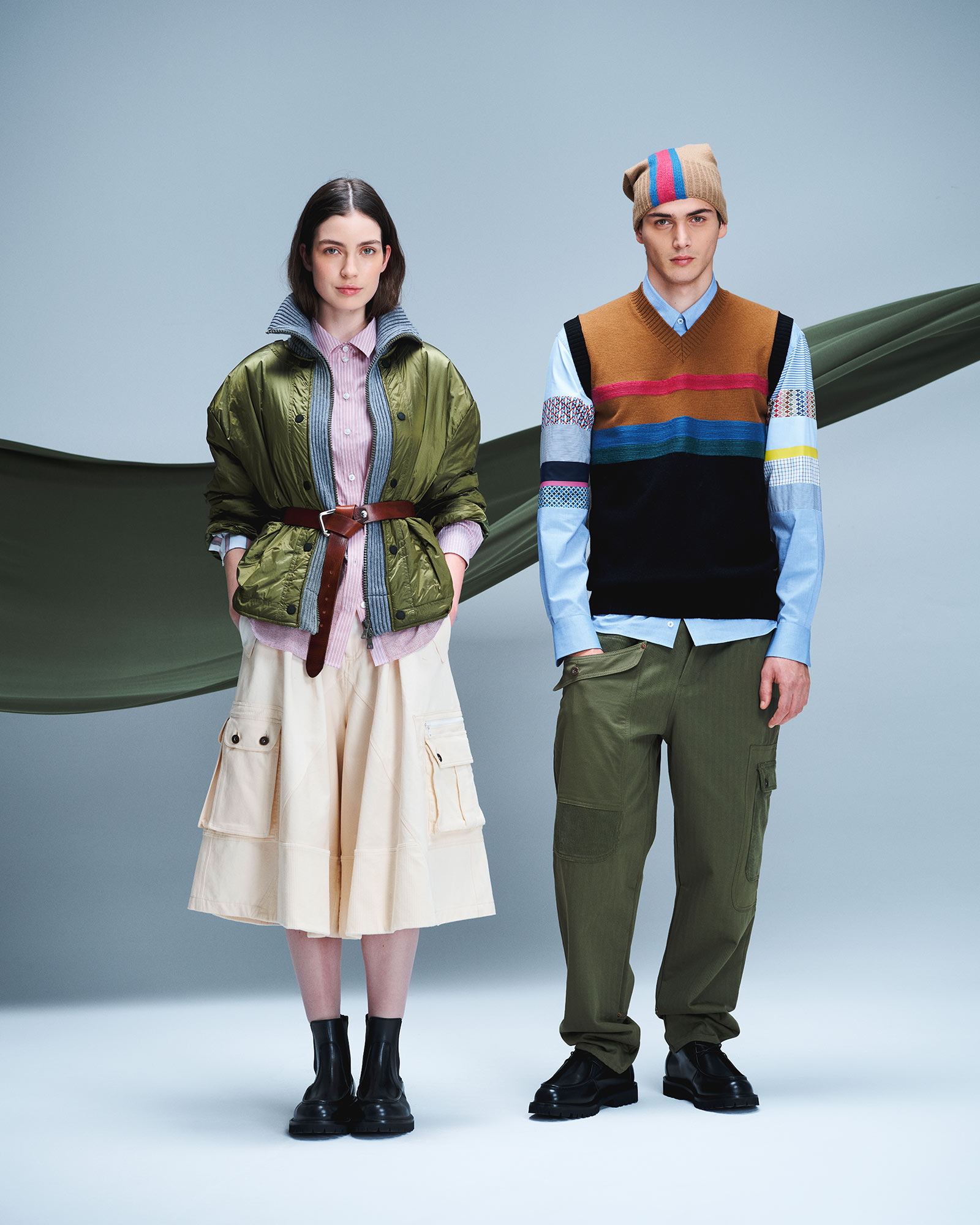 Donna e uomo in look utility; lei con giacca bomber verde e gonna cargo chiara, lui con gilet multicolore e pantaloni cargo verdi